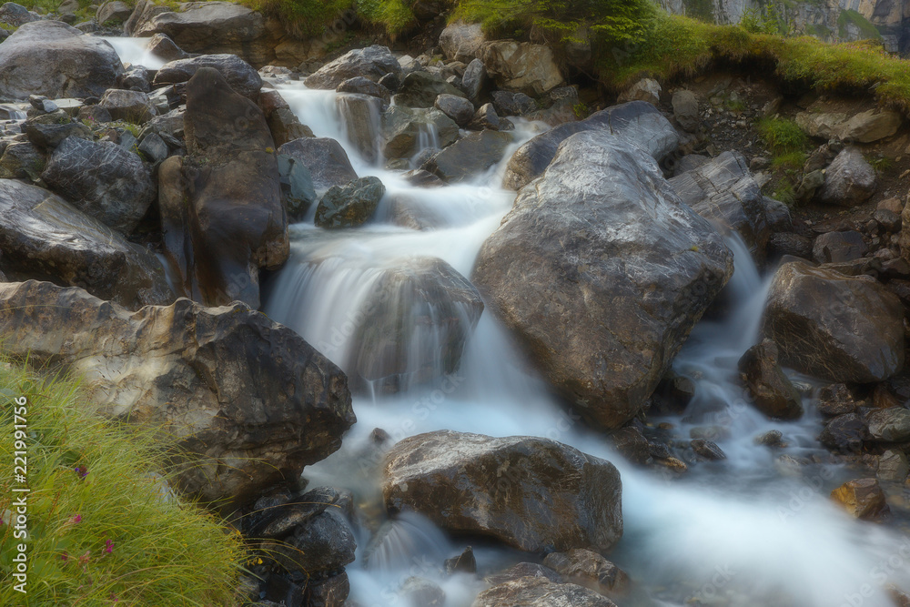 Mountain brook with flowing water on the stones, long exposition, version with a soft filter Mountain brook with flowing water on the stones, long exposition, version with a soft filter