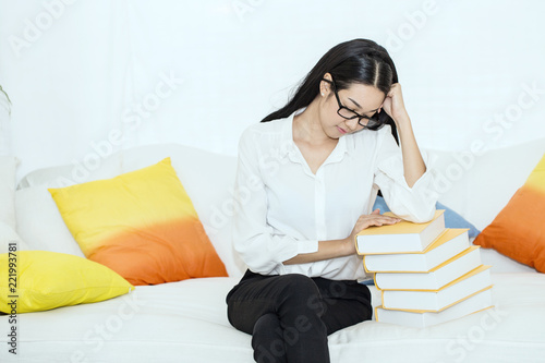 Beautiful Attractive Student Asian Woman stress and tried of her book on sofa want to sleep and rest