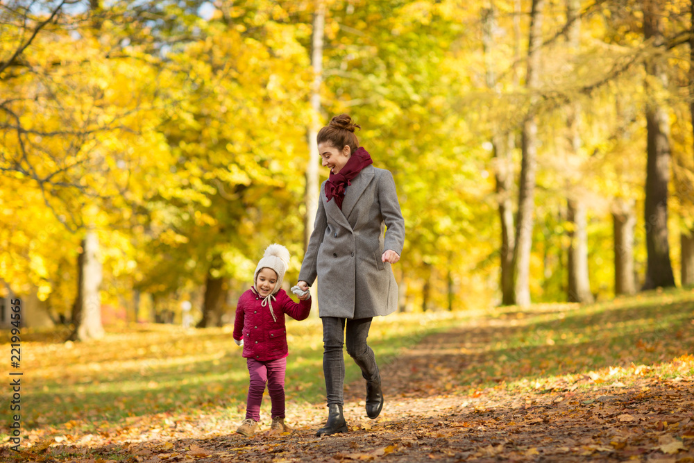 family, season and people concept - happy mother and little daughter walking along autumn park family, season and people concept - happy mother and little daughter walking along autumn park
