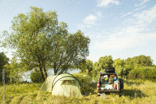 a camp and a jeep with lots of baggage on a river bank