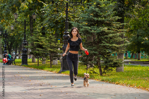 an Asian woman runs around with her four-legged friend. Playing sports with a Yorkshire terrier