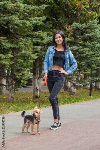 Asian woman on a walk in the park with her pet. Yorkshire Terrier