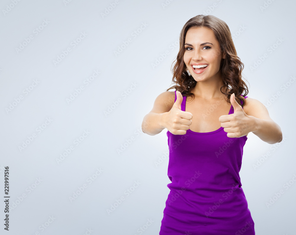 Fototapeta premium Woman showing thumbs up gesture, over grey
