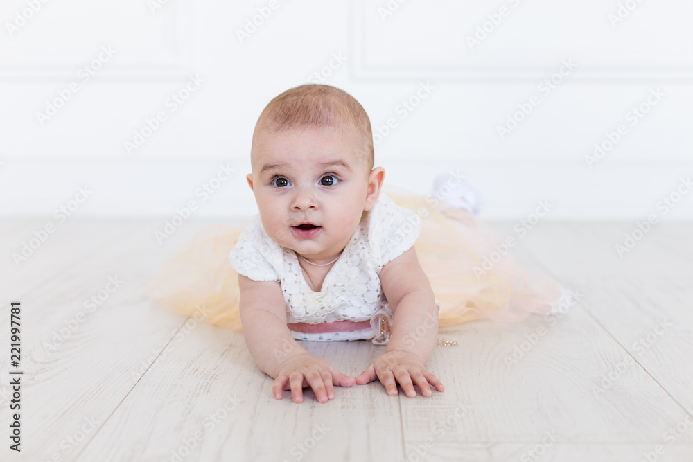 A baby girl is crawling along the floor with an inquisitive and wondering look on her face. Horizontal shot. Cute 6 months girl A baby girl is crawling along the floor with an inquisitive and wondering look on her face. Horizontal shot. Cute 6 months girl