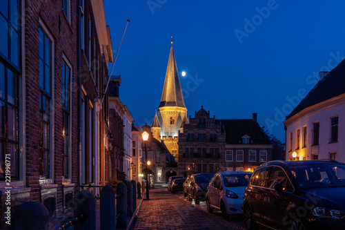 The atmospherically illuminated medieval city gate stands above the medieval city center. Full moon hangs above Historic old fortified town 