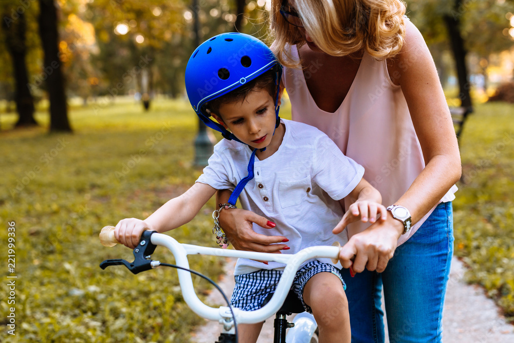 Mother helps her son to ride a bike Mother helps her son to ride a bike