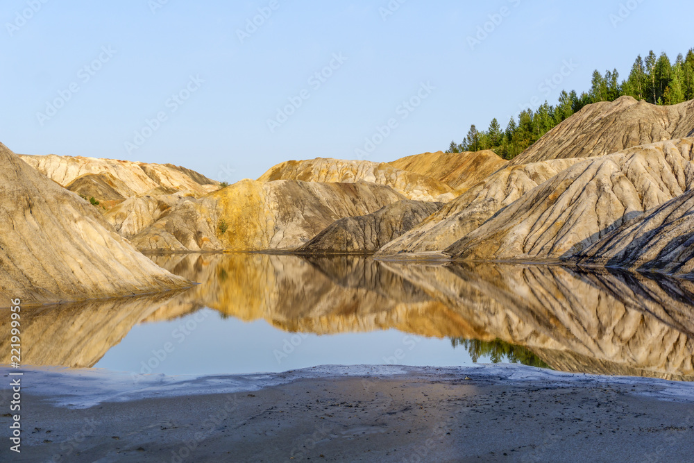 landscape - lake at the bottom of a spent quarry of kaolin mining with beautiful slopes with traces of streams