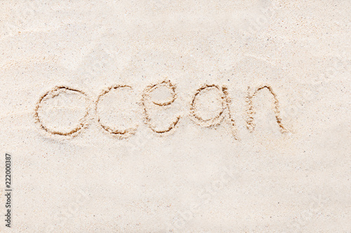 Handwriting words "ocean" on sand