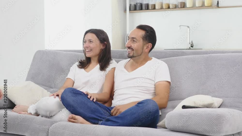 Young couple watching tv with popcorn in the living room. children brings popcorn on the couch Young couple watching tv with popcorn in the living room. children brings popcorn on the couch