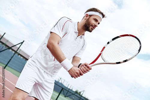 Professional tennis player is doing a kick tennis on a tennis court on a sunny summer morning. The is dressed in sportswear. © Friends Stock