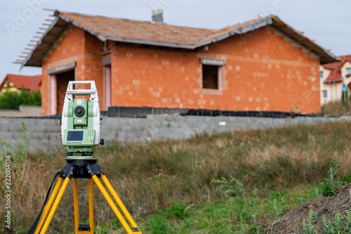 Surveyor equipment (theodolit) on construction site with house and sky  in background