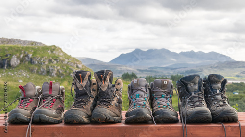 4 paires de chaussures de randonnée sur fond de montagne