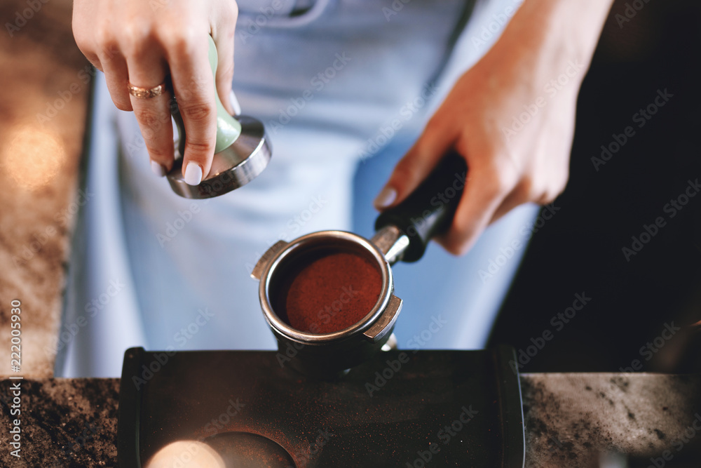 A young pretty slim girl,wearing casual outfit,is cooking coffee in a modern coffee shop. It focuses on the process. A young pretty slim girl,wearing casual outfit,is cooking coffee in a modern coffee shop. It focuses on the process.