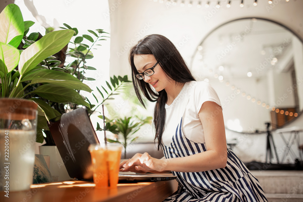 A pretty slim dark-haired girl with glasses,wearing casual style, types something on her laptop in a cozy coffee shop, A pretty slim dark-haired girl with glasses,wearing casual style, types something on her laptop in a cozy coffee shop,