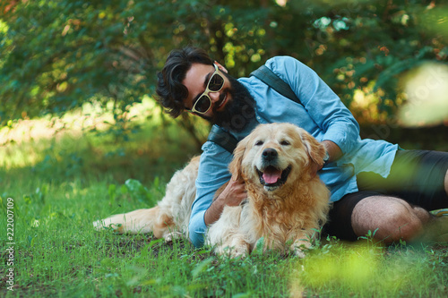 Man with beard and his small yellow dog playing and enjoying sun