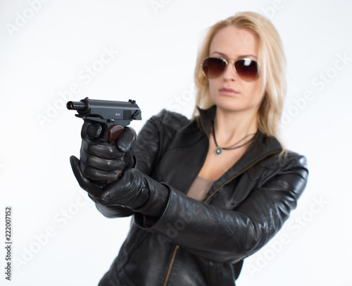 Beautiful young blond woman wearing sunglasses holding a gun