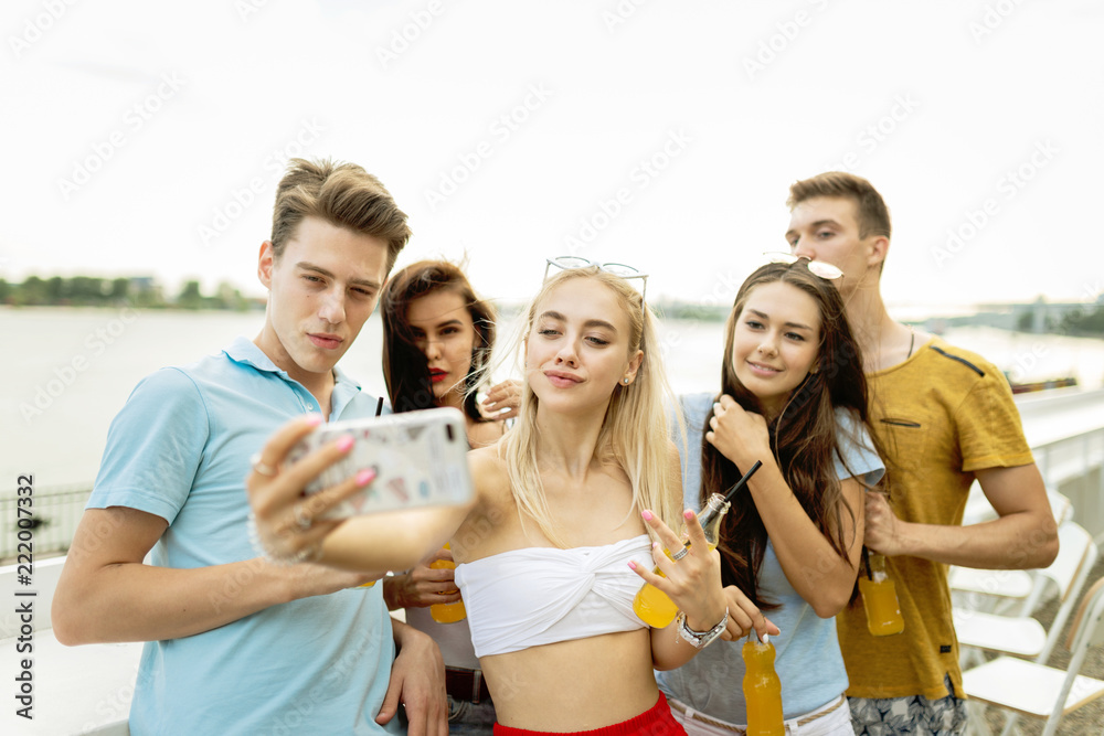 A company of good-looking friends laughing and drinking yellow c