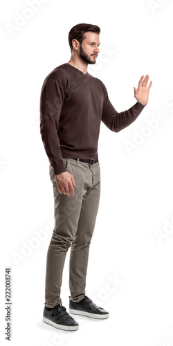 A young bearded man in a side view stands with one hand up and held palm to the front.