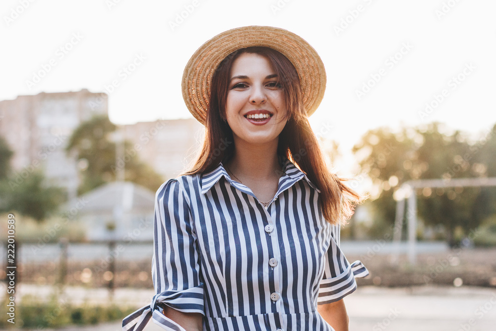 young woman wearing striped dress and straw hat