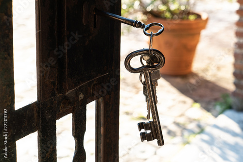 Schlüsselbund mit mehreren alten Schlüsseln, 1 Schlüssel steckt im Schlüsselloch einer alten rostigen Metalltür