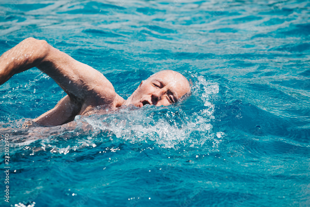 senior man swimming on the blue ocean -health and activity concept.