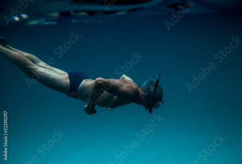 senior man floating underwater on the blue ocean -health and activity concept