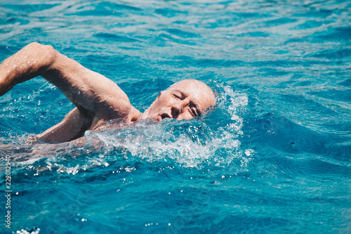 senior man swimming on the blue ocean -health and activity concept.