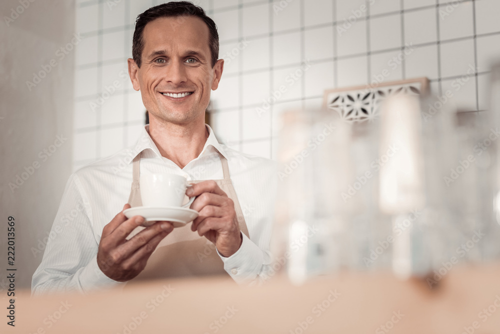 Skilled barista. Cheerful nice man smiling to you while working as a barista in the cafeteria Skilled barista. Cheerful nice man smiling to you while working as a barista in the cafeteria