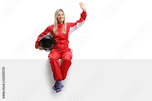 Female racer sitting on a panel and waving
