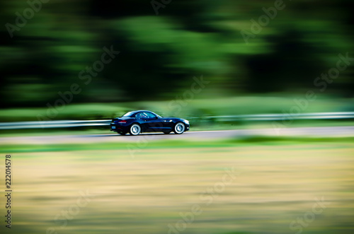 super fast black sports car on the highway slightly blurred against blurred background