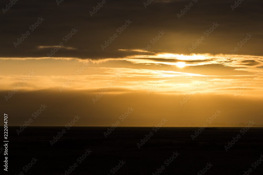 Bright dawn at Mont-Saint-Michel Bay, France, with a black horizon and an orange sky