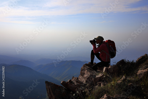 Female tourist taking photo on mountain peak