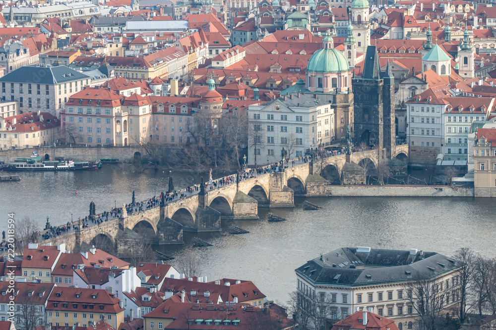 View of Charles Bridge, Old Town Bridge Tower and Church of St. Francis of Assisi. Beautiful Prague cityscape with classic red roofs, Vltava river and famous Czech showplaces.