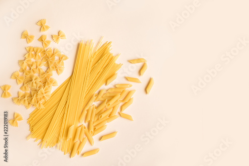various uncooked pasta on pink background