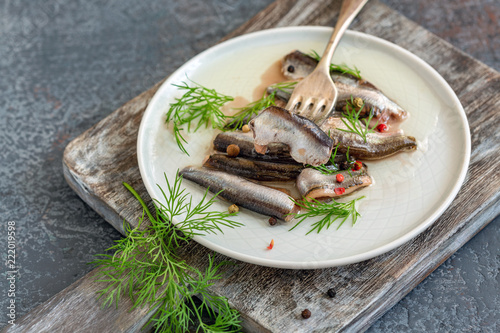 Plate with spicy anchovies in oil with green dill.