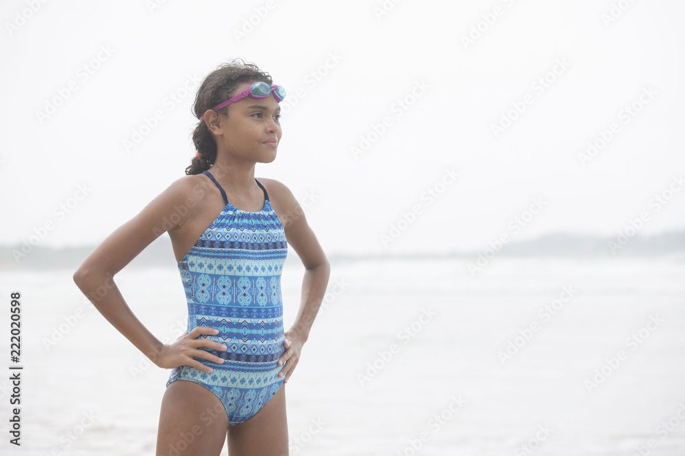 Beautiful curly haired mixed race pre-teen child in swim wear with