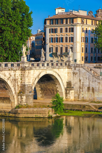 View on the Sant Angelo bridge over the Tiber river in Rome, Italy on a sunny day.