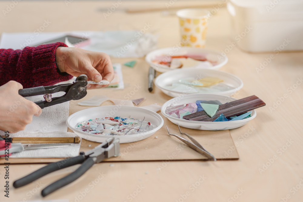 Female hand cutting material on small pieces for mosaic Female hand cutting material on small pieces for mosaic