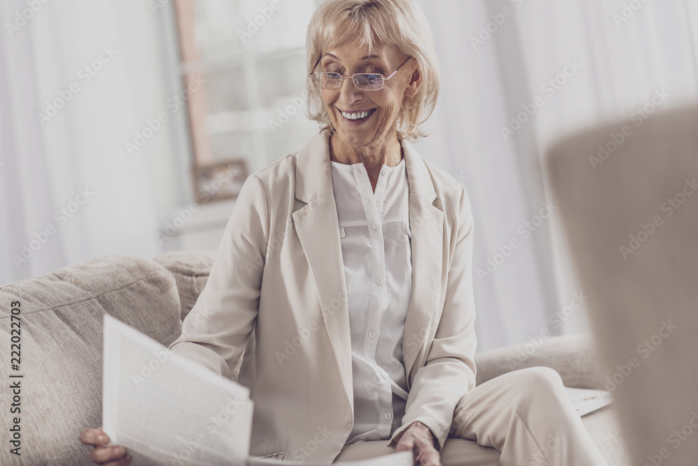 Retired writer. Retired world famous writer wearing glasses feeling pleasant while reading feedback letters from her readers Retired writer. Retired world famous writer wearing glasses feeling pleasant while reading feedback letters from her readers