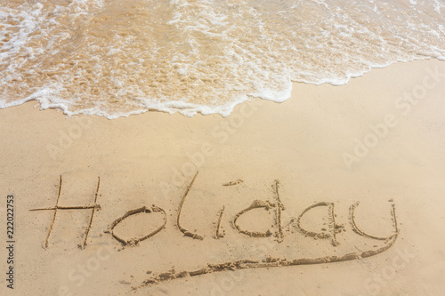 The word holiday written in the sand at the beach