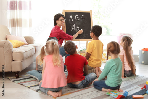 Young woman teaching little children indoors. Learning by playing