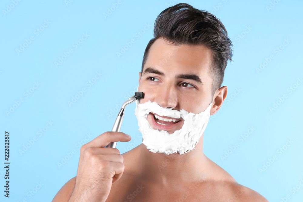 Handsome young man shaving on color background Handsome young man shaving on color background