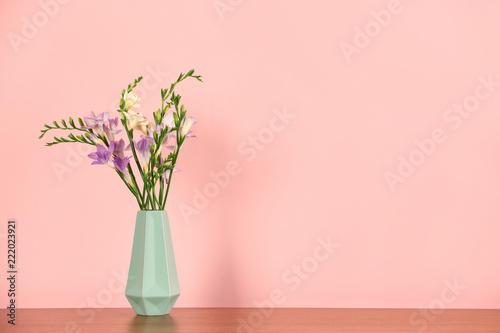 Beautiful fragrant freesia flowers in vase and space for text on color background © New Africa