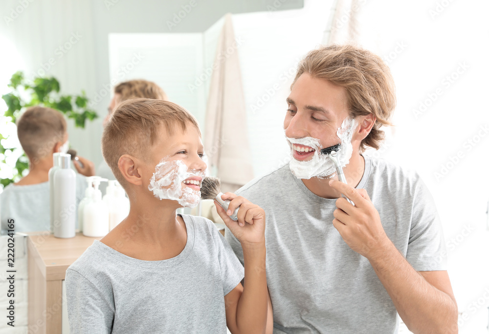 Father and son shaving together in bathroom