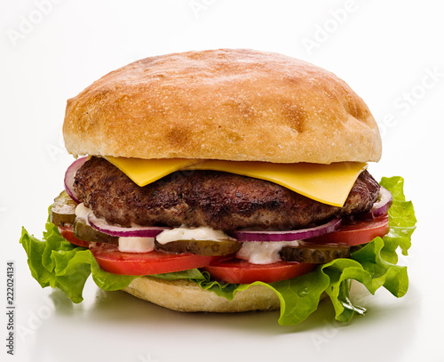 Classic cheeseburger with salad, tomato and pickled cucumbers on a white background. Isolated