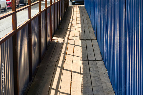 pedestrian crossing with a canopy of corrugated metal blue sheet metal and dervish flooring along the construction site with a dangerous zone