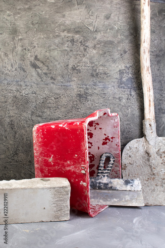 Building tools old, dirty shovel , red bucket, bricks on the gray concrete background. Copy space. Top view. photo