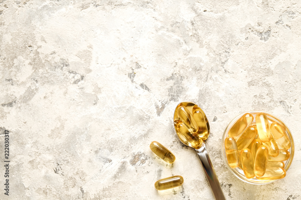 Bunch of omega 3 fish liver oil capsules in silver spoon. Close up of big golden translucent pills in pile. Healthy every day fatty acids nutritional supplement dosage. Top view, flat lay, copy space. Bunch of omega 3 fish liver oil capsules in silver spoon. Close up of big golden translucent pills in pile. Healthy every day fatty acids nutritional supplement dosage. Top view, flat lay, copy space.