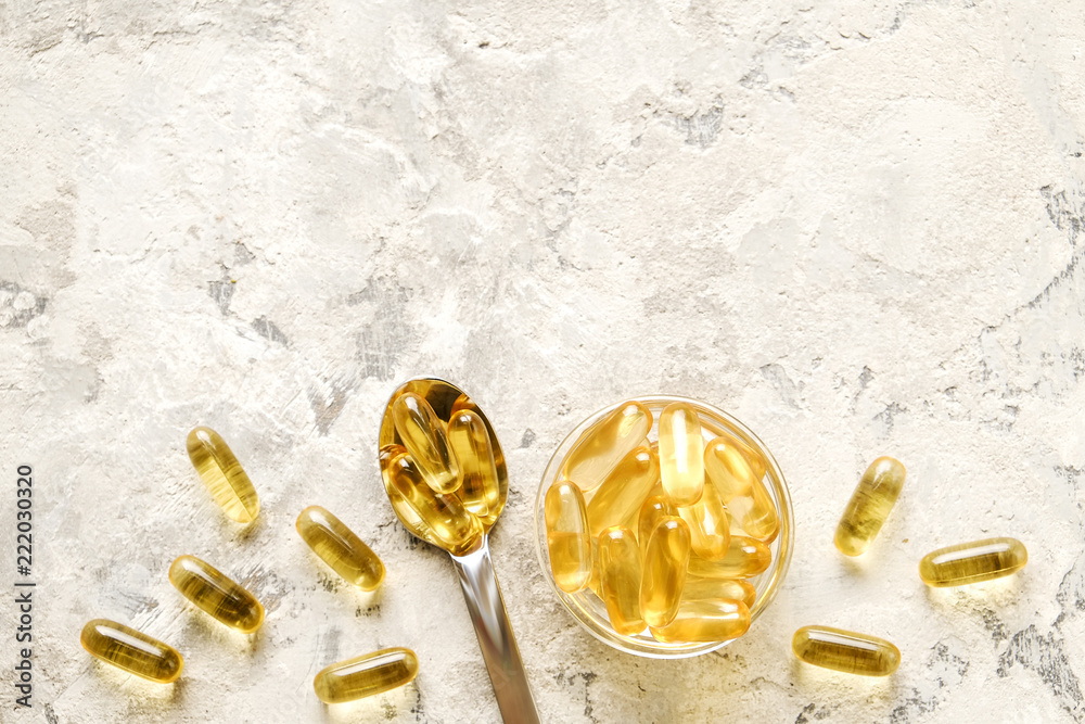 Bunch of omega 3 fish liver oil capsules in silver spoon. Close up of big golden translucent pills in pile. Healthy every day fatty acids nutritional supplement dosage. Top view, flat lay, copy space. - obrazy, fototapety, plakaty 