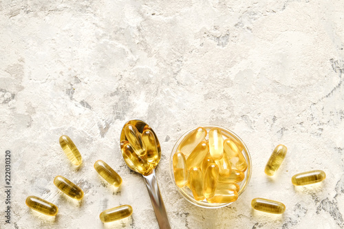 Bunch of omega 3 fish liver oil capsules in silver spoon. Close up of big golden translucent pills in pile. Healthy every day fatty acids nutritional supplement dosage. Top view, flat lay, copy space. photo